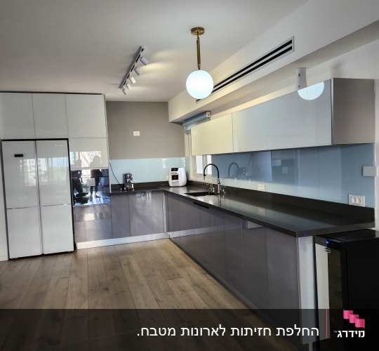 מטבח מודרני עם ארונות אפורים ומשטח עבודה כהה